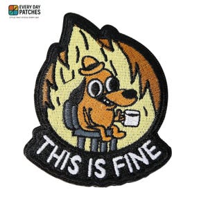 Könnte beinhalten: Gestickter Aufnäher mit einem Cartoon-Hund, der in einem brennenden Raum sitzt und eine Kaffeetasse hält. Der Aufnäher trägt den Text "THIS IS FINE" in Weiß auf schwarzem Grund, mit einem gelb-braunen Flammendesign.