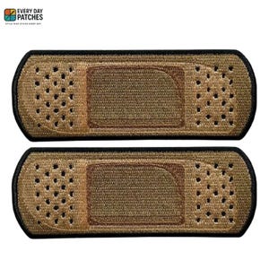 Può includere: Due toppe ricamate a forma di cerotto. Le toppe sono beige con un centro marrone più scuro e un bordo nero. Le toppe hanno piccoli fori su ogni estremità. Il testo "EVERY DAY PATCHES" e "STYLE THAT STICKS EVERY DAY" si trova nell'angolo in alto a sinistra.