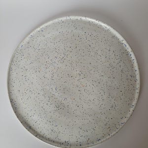 Könnte beinhalten: Ein Set aus drei Keramikbechern mit gesprenkelter, matter Oberfläche. Die Becher sind in den Farbtönen Creme, Hellgrau und Dunkelgrau gehalten. Jeder Becher hat ein schlichtes, minimalistisches Design, ideal für Kaffee oder Tee.