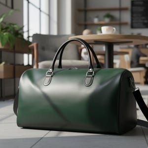 Könnte beinhalten: Eine dunkelgrüne Leder-Reisetasche mit schwarzen Griffen und einem Schultergurt. Die Tasche hat eine rechteckige Form und einen Reißverschluss. Die Griffe sind mit silberfarbener Hardware befestigt. Die Tasche steht auf einem gefliesten Boden.