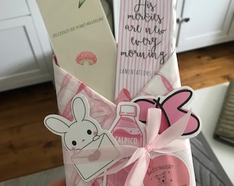 May include: Two rectangular paper bookmarks inside a pink and white patterned envelope. One bookmark features a small flower, a mushroom, and the text BLESSED BEYOND MEASURE. The other features pink bows and the text His mercies are new every morning.