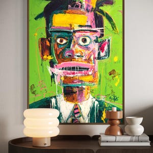 Puede incluir: Pintura de retrato abstracto con fondo verde, que presenta un rostro con colores llamativos como amarillo, rosa y naranja. El sujeto lleva una camisa blanca y una corbata a rayas rosas y negras. La obra est&aacute; enmarcada en un marco de madera marr&oacute;n.