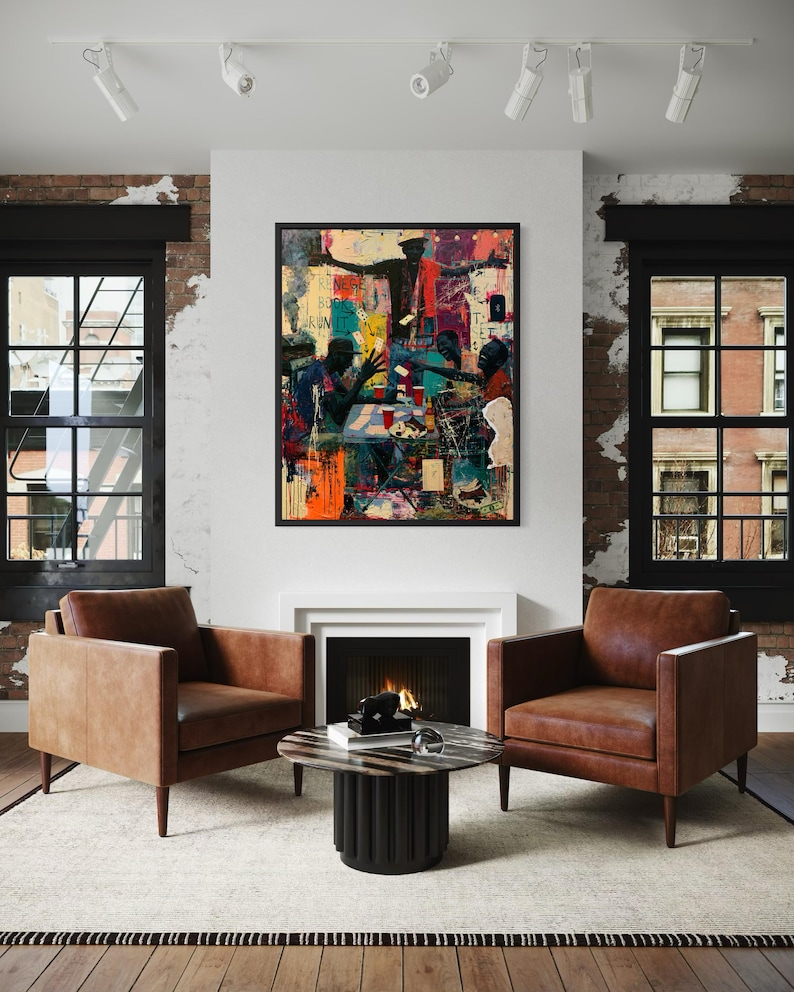 May include: A framed rectangular wall art piece featuring a vibrant, multi-colored mixed media illustration of several figures gathered around a table, displayed above a fireplace between two brown leather armchairs and a round coffee table.