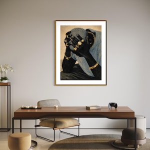May include: A framed art print featuring a person with their hands covering their face. The person is wearing gold jewelry, including rings, bracelets, and a chain. The artwork is displayed in a room with modern furniture and decor.