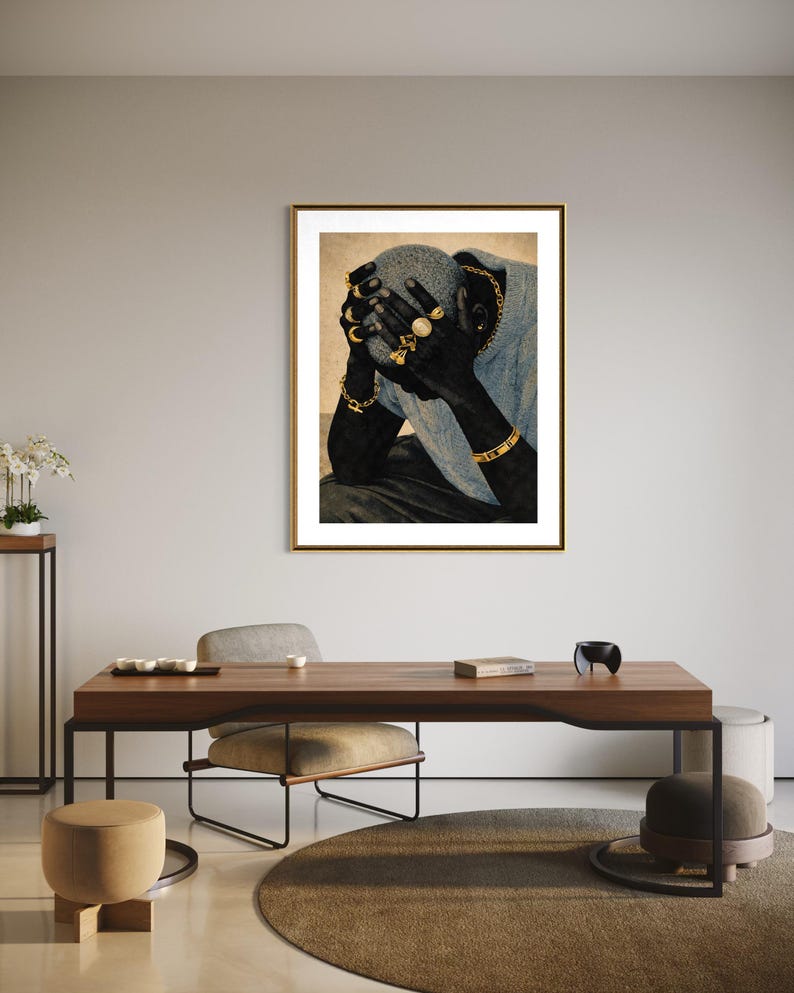 May include: A framed art print featuring a person with their hands covering their face. The person is wearing gold jewelry, including rings, bracelets, and a chain. The artwork is displayed in a room with modern furniture and decor.