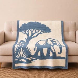 May include: A rectangular crochet blanket featuring a cream-colored background with a blue graphic pattern. The design depicts a large elephant walking past a tall acacia tree and a small bush, all bordered by a solid blue crocheted edge.