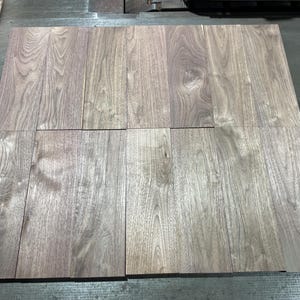 May include: A collection of rectangular wooden planks, arranged in a grid pattern. The wood has a natural grain and a mix of light and dark brown tones. The planks appear to be ready for use in a woodworking project.