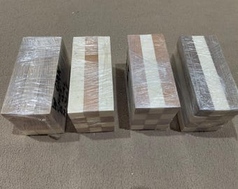 May include: Four rectangular wooden blocks wrapped in clear plastic. The blocks feature alternating patterns of light and dark wood, some with checkerboard designs. The blocks are likely for a craft or building project.