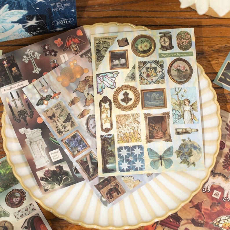 Retro-style collage sticker sheets displayed on a ceramic plate, featuring floral, botanical, frame, and fantasy illustrations for journaling and scrapbooking.
