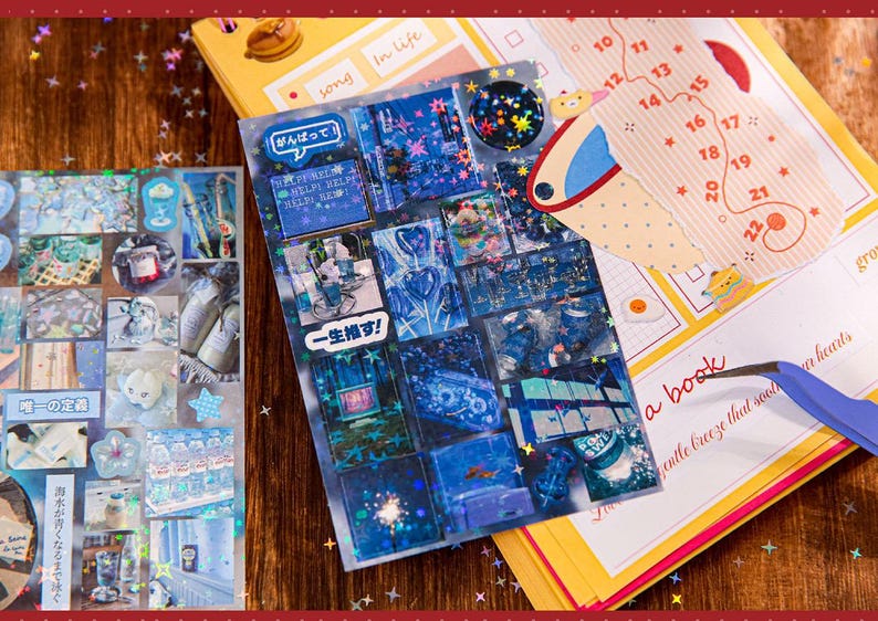 May include: A collection of decorative stickers with various designs, including blue cityscapes, Japanese text, and a calendar. The stickers are arranged on a wooden surface with other stationery items.