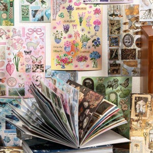 May include: A collection of decorative stickers and sticker sheets featuring floral, butterfly, and vintage-themed designs. The stickers are in various colors, including pink, blue, and green, and are arranged on a white background. Some sheets have text that reads "In the fields" and "Sunny day".