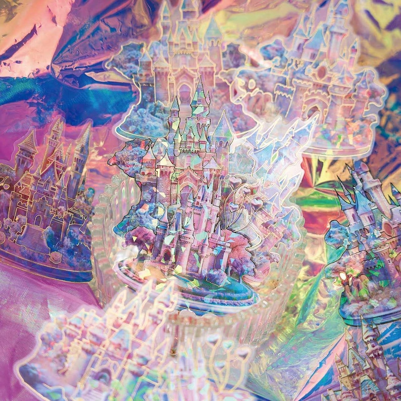 Op de afbeelding: Een verzameling iriserende stickers met sprookjeskastelen in roze, blauw en goud. De stickers hebben een holografisch effect, waardoor een glinsterend, veelkleurig uiterlijk ontstaat. De kastelen zijn gedetailleerd met torentjes en omliggende landschappen.