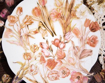 May include: A collection of floral stickers featuring tulips in shades of peach, pink, and gold. The stickers are arranged on a white, scalloped-edge surface, creating a delicate and artistic display. The stickers are ideal for scrapbooking, card making, or other craft projects.