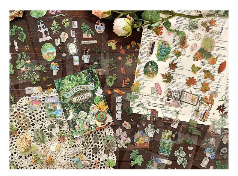 May include: A collection of decorative stickers featuring botanical and nature-themed designs. The stickers include images of plants, leaves, and small illustrations, along with a sticker book. The stickers are arranged on a wooden surface with floral accents.