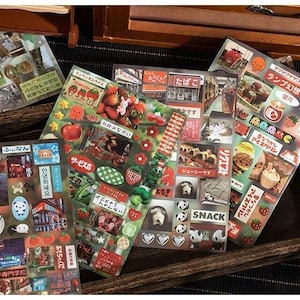 Op de afbeelding: Een verzameling decoratieve stickers met Japanse thema's. De stickers tonen afbeeldingen van eten, dieren en Japanse tekst. De stickers zijn gerangschikt op transparante vellen, met een verscheidenheid aan kleuren en vormen.