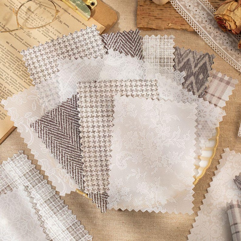 May include: A collection of fabric swatches in various patterns and textures. The swatches include white lace, herringbone, and houndstooth designs in neutral tones. The fabrics are arranged on a neutral surface, suggesting a craft or design theme.
