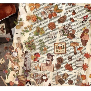 May include: A collection of vintage-style stickers featuring botanical and woodland elements. The stickers include illustrations of mushrooms, leaves, acorns, butterflies, and a bear. The background is a collage of old book pages.