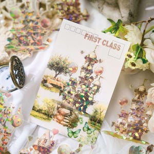 Op de afbeelding: Een ansichtkaart met een kasteelillustratie en de tekst "FIRST CLASS". De kaart is omgeven door decoratieve stickers met kasteel- en hartontwerpen, een vintage zakhorloge en bloemen.