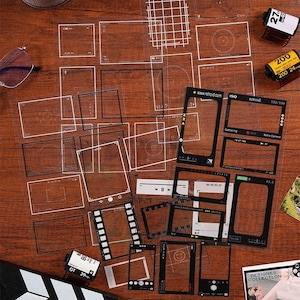 May include: A collection of clear, transparent stickers with various frame designs, film strips, and camera-related graphics. Includes film rolls, a clapperboard, and text like "Retro Camera" and "Designs Collection".
