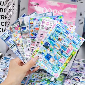 May include: A collection of multi-coloured sticker sheets featuring various digital-themed graphics, including computer windows, icons, ocean scenes, and star borders. The sheets display a variety of small, detailed illustrations in blue, pink, and white tones, arranged in grid patterns on clear backing paper.