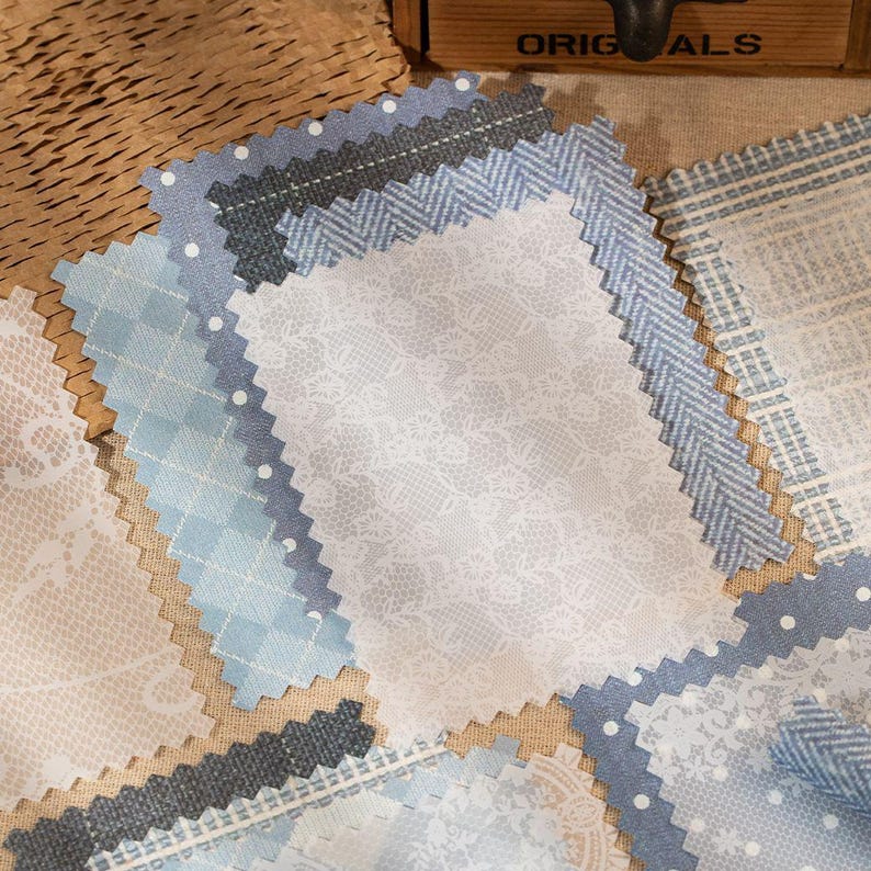 May include: Assortment of fabric swatches in various shades of blue, gray, and white. Patterns include polka dots, lace, and herringbone. The edges are cut with a zig-zag pattern. The word "ORIGINALS" is visible on a wooden box in the background.