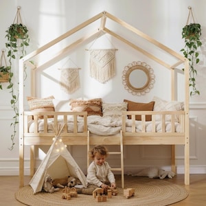 Peut inclure: Un lit mezzanine en bois clair avec un cadre en forme de maison, une échelle et un petit tipi. Le lit est décoré d'oreillers et de couvertures. Des plantes suspendues et un tapis rond complètent la chambre d'enfant aux tons neutres.