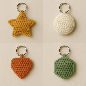 Op de afbeelding: Vier handgemaakte gehaakte sleutelhangers in verschillende vormen: een ster, een cirkel, een hart en een zeshoek. De ster is mosterdgeel, de cirkel is gebroken wit, het hart is oranje en de zeshoek is olijfgroen. Elke sleutelhanger heeft een zilveren metalen ring.