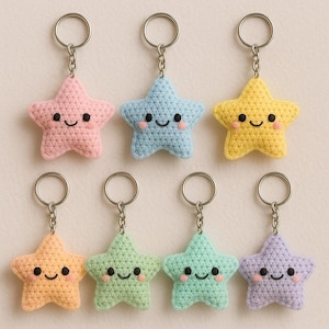 Puede incluir: Colección de siete llaveros de estrella de ganchillo en varios colores pastel: rosa, azul, amarillo, naranja, verde, turquesa y morado. Cada estrella tiene una cara sonriente con ojos negros y una boca curvada, y está unida a un llavero plateado.