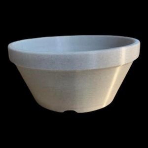May include: A light beige, circular mixing bowl with a smooth, matte finish. The bowl features a wide, thick rim at the top and a tapered body that narrows toward the base. The interior and exterior surfaces are a consistent, solid neutral color.