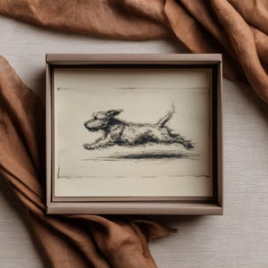 May include: A framed black and white sketch of a dog in mid-run. The artwork is in a rectangular, light brown frame, set against a backdrop of a brown fabric. The dog is depicted with detailed shading, capturing its movement.