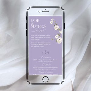 以下が含まれることがあります： スマートフォン画面に表示されたデジタル結婚式の招待状。招待状には、エレガントな筆記体で「JADE & MATHÉO」の名前が記載され、花のアクセントとフランス語でのイベントの詳細が記載されています。背景はソフトラベンダー色です。