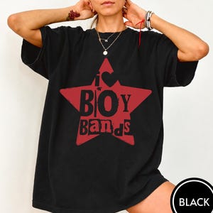 Puede incluir: Una camiseta negra de manga corta con un gr&aacute;fico de una estrella roja grande en el pecho. Dentro de la estrella, el texto dice I s&iacute;mbolo de coraz&oacute;n BOY BANDS en letras negras en negrita. La camiseta tiene cuello redondo y corte holgado.