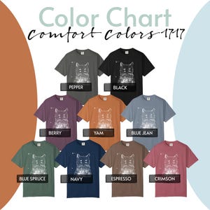May include: A colour chart for Comfort Colors 1717 t-shirts featuring a white graphic of a four-eyed cat. The shirt colours include pepper, black, berry, yam, blue jean, blue spruce, navy, espresso, and crimson, each labelled with its respective name.