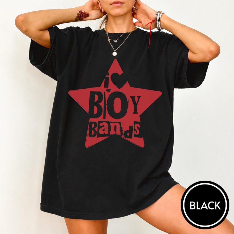 Puede incluir: Una camiseta negra de manga corta con un gr&aacute;fico de una estrella roja grande en el pecho. Dentro de la estrella, el texto dice I s&iacute;mbolo de coraz&oacute;n BOY BANDS en letras negras en negrita. La camiseta tiene cuello redondo y corte holgado.