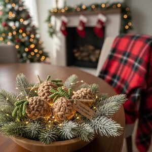 May include: A wooden bowl centerpiece with crocheted pineapples, evergreen branches, and fairy lights. The pineapples are brown with green tops. A small tag reads "Handmade for Christmas". The background includes a Christmas tree and fireplace.