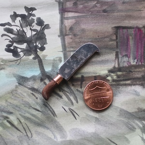 May include: A miniature, curved blade knife with a wooden handle and copper ferrule, next to a US one-cent coin. The knife is set against a watercolor painting of a landscape with a tree and a building.
