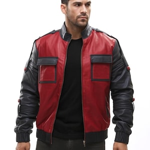 Puede incluir: Chaqueta de cuero roja y negra de estilo bomber. La chaqueta tiene cuello, puños y dobladillo de canalé negros. Las mangas son negras y el cuerpo es rojo con dos bolsillos cuadrados negros. Tiene cierre de cremallera.