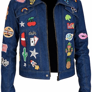 May include: A blue denim jacket adorned with colorful patches. Patches include a rainbow, cherry, cactus, rocket, and the word "LOVE". The jacket has a collared neckline, long sleeves, and a zipper closure. A fun and unique fashion statement.