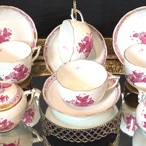 May include: A white ceramic mug with a black handle and the text "But First, Coffee" in a black, handwritten-style font. The mug is on a white surface.