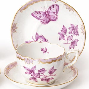 May include: A white ceramic mug with a black handle and the text "But First, Coffee" in a black, handwritten-style font. The mug is on a white surface.