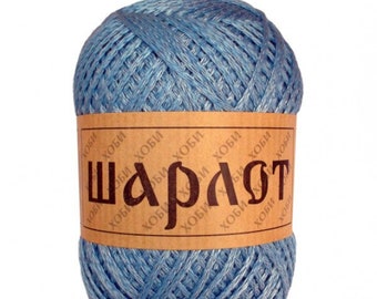 May include: A ball of light blue yarn with a brown label wrapped around it. The label has the word "Шарлот" in large, dark brown Cyrillic letters. The yarn is tightly wound, and the label also has smaller text in a different font.