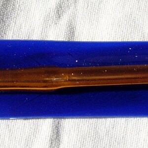 May include: A gold-colored crochet hook in a blue plastic case.