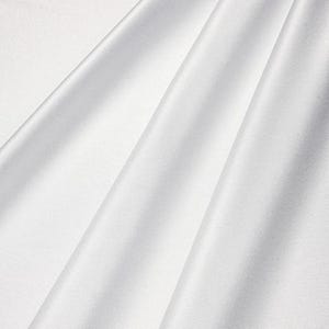 May include: A close-up of white fabric with soft folds and subtle shadows. The fabric appears smooth and has a slight sheen, suggesting a luxurious material. The folds create a sense of depth and texture.