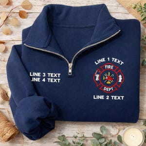 May include: Navy blue quarter-zip sweatshirt with a white zipper and a fire department emblem. The emblem is red and features a Maltese cross design with the words "FIRE DEPT" and space for custom text.