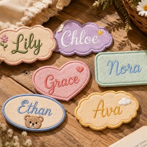 Peut inclure: Six écussons en tissu brodés avec des noms et des motifs. Lily sur un nuage beige avec une fleur, Chloe sur un nuage violet avec une étoile, Nora sur un rectangle menthe avec une marguerite, Grace sur un cœur rose, Ethan sur un ovale bleu avec un ours, et Ava sur un nuage jaune avec une petite icône de nuage.