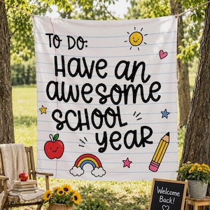 Puede incluir: Una pancarta de tela blanca con líneas horizontales azules que recuerdan a una hoja de papel. El texto dice TO DO: Have an awesome SCHOOL year en negro. Las ilustraciones incluyen un sol amarillo, una manzana roja, un arcoíris y un lápiz amarillo.