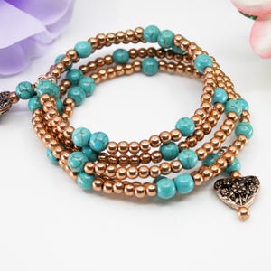 May include: A multi-strand bracelet with turquoise and copper beads. The bracelet has two heart-shaped charms.