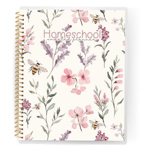 May include: Homeschool undated planner with a floral design. The cover features watercolor illustrations of pink and purple flowers, green leaves, and bees on a cream background. The spiral binding is gold.