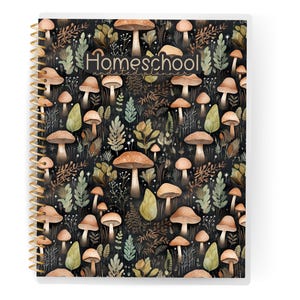 May include: A spiral-bound notebook with a cover featuring a repeating pattern of brown mushrooms, green leaves, and foliage on a black background. The word "Homeschool" is printed in a script font across the top. The spiral binding is gold.