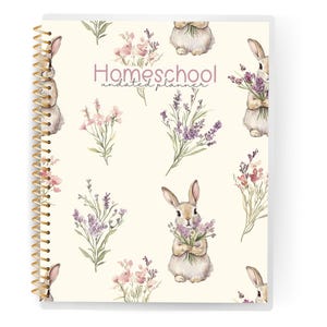 May include: Homeschool undated planner with a cream background featuring watercolor illustrations of bunnies holding lavender and pink flowers. The planner has a gold spiral binding.